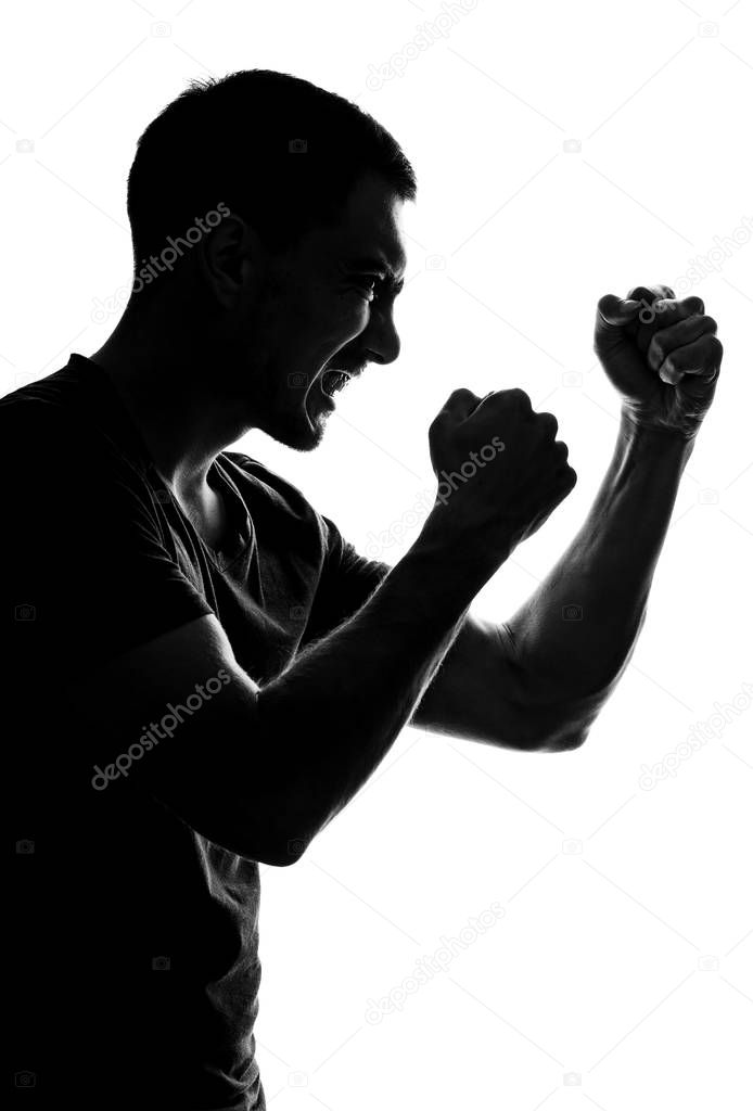 silhouette of an aggressive man in profile with grin, fists folded in front of him