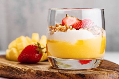 Mango smoothie tatlısı yakın çekim, ricotta peynir krema, çilek parçaları ile pişmiş müsli