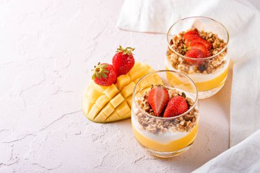 mango smoothie, ricotta peyniri, granola ve güzel dilimlenmiş mango ve kopya alanı ile çilek meyve tatlı ile iki bardak üst görünümü