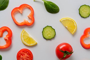 Beyaz arka plan ile dilimlenmiş salatalık, domates, limon, biber ve ıspanak yaprakları ile Düz yatıyordu tasarım