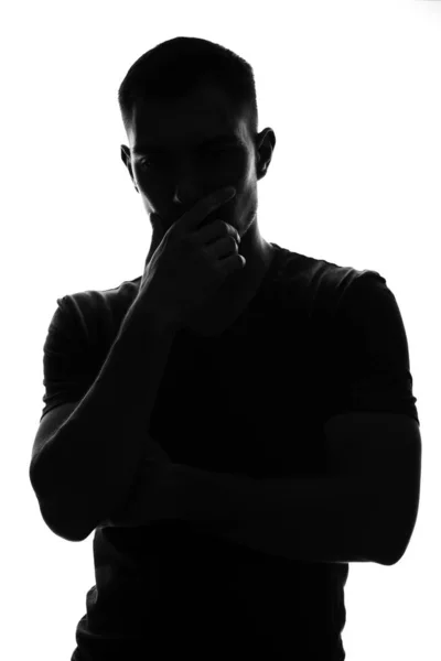 Silhouettenporträt eines nachdenklichen jungen Mannes, der seine Hand vor sein Gesicht hält, die Pose eines Denkers — Stockfoto