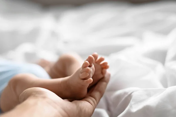 Macro plan little legs newborn baby in big men 's palm father' s, concept care, paternity, guardianship . — стоковое фото