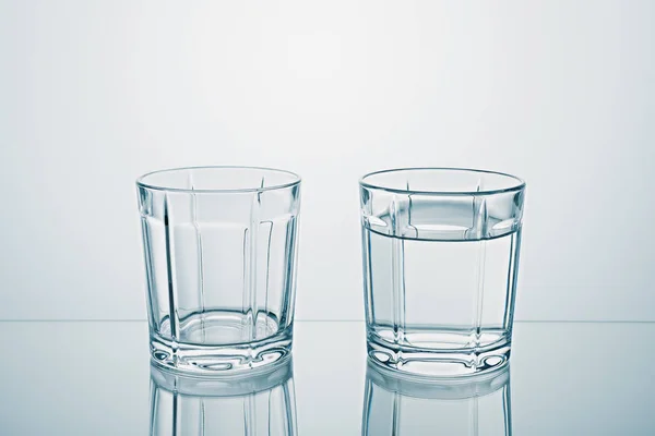 Dos vasos uno vacío, uno lleno de agua limpia — Foto de Stock