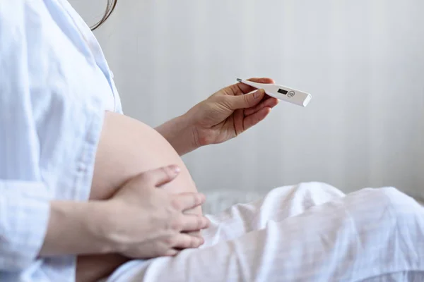 Ung gravid kvinna i sängen med termometer, närbild — Stockfoto