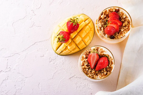 Sobremesa vista superior com manga e mousse de queijo decorado com morango e granola com guardanapo branco sobre fundo rosa claro — Fotografia de Stock