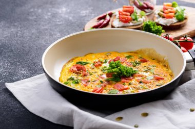 koyu bir arka plan üzerinde domates ve yeşillik ile bir tavada omlet, sağlıklı vegan Kahvaltı