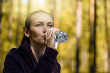 Yakın plan esmer kadın susuzluğunu gideriyor, Park 'ta şişeden su içiyor.