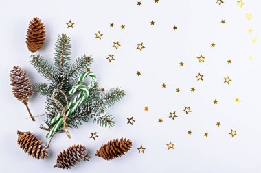 Ladin dalları, koniler, yeşil lolipoplar, beyaz arka planda parıldayan yıldızlar, Noel kompozisyon konsepti