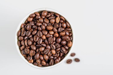 Üst manzara kavrulmuş kahve çekirdekleri beyaz arka planda ve fotokopi alanı var.