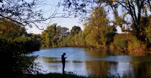 Silhouette of a fly fisherman in Krka river, Slovenia, Europe