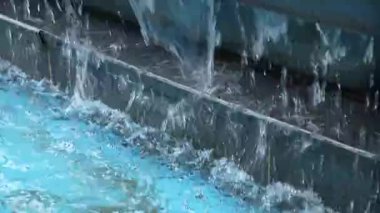 Şehir parkında asfalt bir meydanda akan suyla modern taş çeşme. Yüksek kalite 4k görüntü