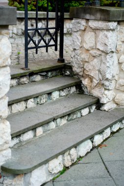 Dışarıdaki taştan merdivenler, ıslak adımlarla siyah işlemeli demir kapı, taştan duvarları ve eski kaldırımları olan kırsal yapı..