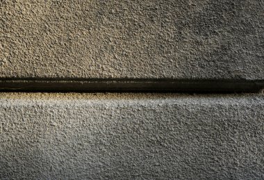 Yatay çizgileri ve aydınlık gölgeleri olan sert beton duvar yüzeyine yakın çekim.