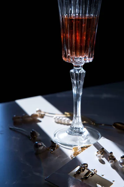 桌上放着精致迷人的珍珠珠宝 桌上放着一杯粉色或红酒 浪漫极了 — 图库照片