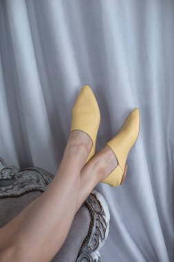 Ayakları üzerinde duran kadınlar için sarı ayakkabılar ve yaşam tarzında bir odada izole edilmiş, topuksuz, parlak renkli ve trendi olmayan rahat şık ayakkabılar.