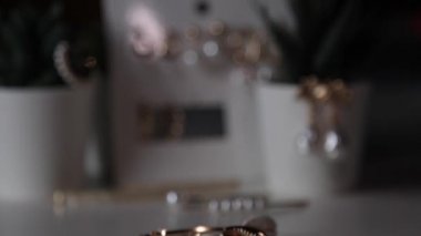İnci, küpe ve saç tokaları olan modern stil pahalı ve lüks altın mücevherlerin bir koleksiyonu, kapalı alan çiçeklerinin arka planında, bir kadının masasında yatıyor.