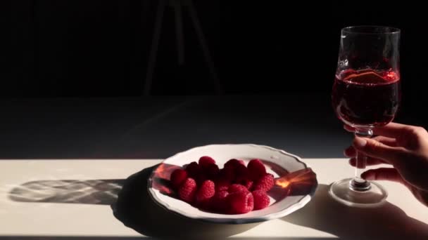在盘子里放上覆盆子 在桌子上或酒吧里放上一杯粉红色或红酒 用水果和酒精庆祝爱情 女孩的手倒入葡萄酒 喝了一杯 — 图库视频影像
