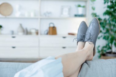 Modern tarzda şık kadın ayakkabıları giymiş bacaklar. Aydınlık bir odada ya da ofiste bir koltukta rahatlayın.