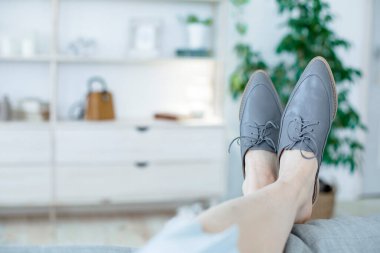 Modern tarzda şık kadın ayakkabıları giymiş bacaklar. Aydınlık bir odada ya da ofiste bir koltukta rahatlayın.