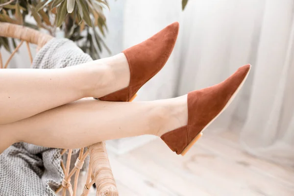 fashionable womens shoes without heels, mules and loafers, on female legs, a girl in a dress and shoes, resting at home in the bedroom, reading a magazine, trending shoes for advertising, in a basket