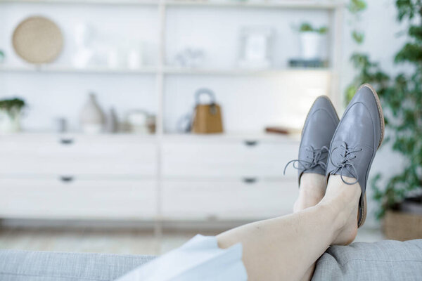 ноги в стильной женской обуви в современном стиле расслабиться на диване в светлой комнате или офисе
