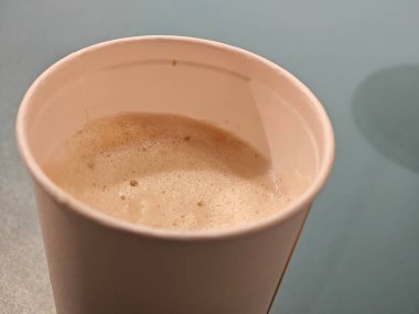 Tek kullanımlık köpüklü kahve masanın üzerinde duruyor. Tipik sosyal öğleden sonra toplantılarının rahatlatıcı atmosferini yansıtır ve dostlar arasındaki sohbeti davet eder..