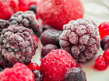 A variety of frozen berries, including raspberries, strawberries, blueberries, and blackberries, are piled together, showcasing their vibrant colors. These fruits are ideal for smoothies or desserts