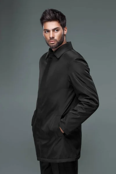 Homem bonito com um corte de cabelo na moda em casaco preto, camisa preta — Fotografia de Stock