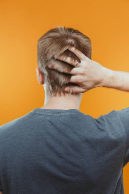 stüdyoda parmaklarıyla saçlarına dokunan adamın arka görünümü