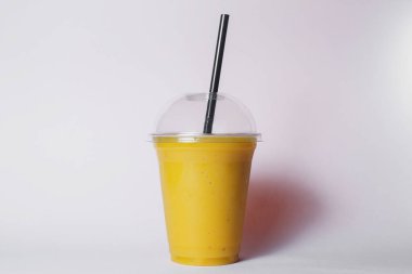 disposable cup of tropic fruit smoothie with straw on studio background