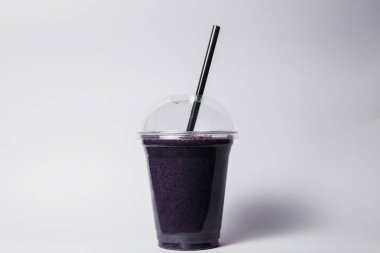 disposable cup of berry smoothie with straw on studio background