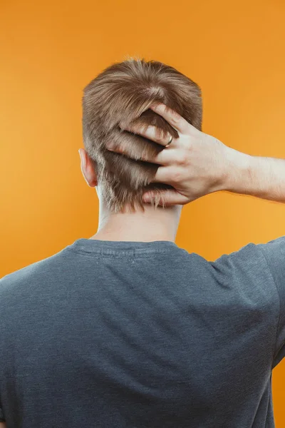 stüdyoda parmaklarıyla saçlarına dokunan adamın arka görünümü