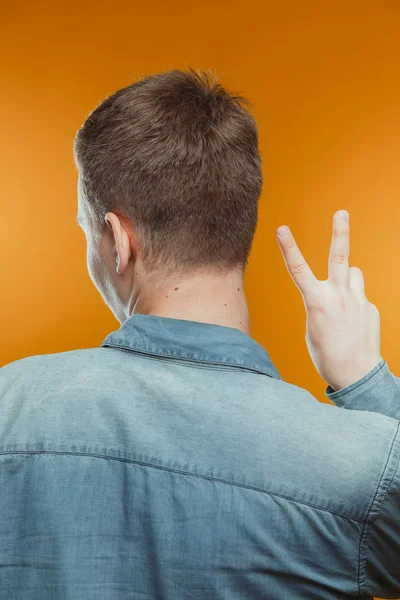 barış işareti gösteren stüdyoda genç adamın arka görünümü