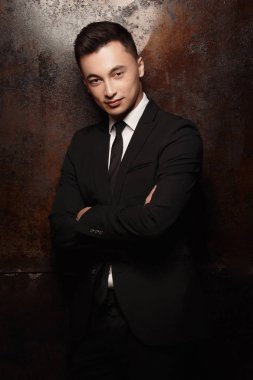 çapraz kolları ile stüdyoda poz takım elbise giyen genç adam