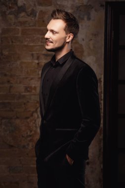 stüdyoda poz takım elbise giyen gülümseyen genç adam