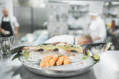 buz ve deniz ürünleri ve mutfak üzerinde çalışan defokus insanlar ile metal plaka