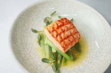 yeşillikli balık bifteği tabağında servis edilen porsiyon