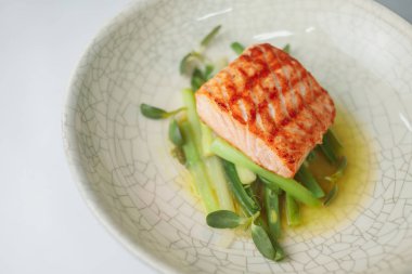 yeşillikli balık bifteği tabağında servis edilen porsiyon