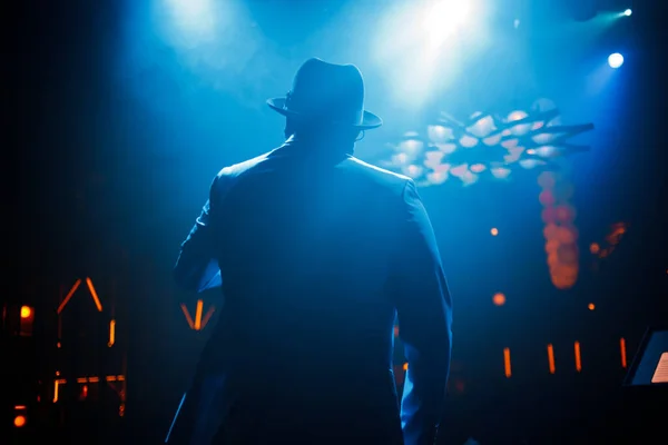 穿着西服 头戴帽子 穿着深色皮肤的歌手 站在舞台上 蓝光闪烁着 优质照片 — 图库照片