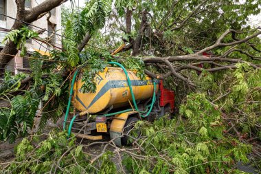 Kolkata, Batı Bengal, Hindistan, 20 Mayıs 2020: Kolkata şehir yolundaki köklerinden sökülmüş bir ağaç gövdesinden hasar gören içme suyu taşımak için kullanılan tanker görüntüsü ile kasırga 