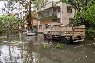 Kolkata, West Bengal, India, May 20, 2020: Water logged city road with stranded vehicles, pedestrians and uprooted trees after severe cyclonic storm 