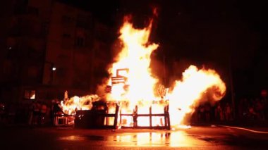 Şenlik ateşi yakmış insanlar geçip gider.