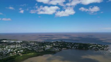 Colonia del Sacramento Uruguay 'ın yüksek irtifa manzarası tarihi çeyrek modern şehir alanlarını ve Rio de la Plata' yı gösteriyor. Geniş kahverengi nehir mavi bir gökyüzünün altında ufka kadar uzanıyor.