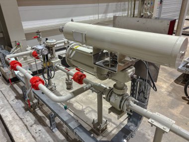 Bir üretim ya da işleme tesisinde ayrıntılı endüstriyel valf ve boru tesisatı. Mühendislik hassasiyeti ve mekanik altyapıyı gösteriyor.