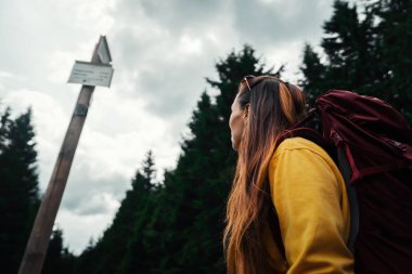 Sırt çantasında orman Dağları aşarak uzun bir yürüyüş sırasında arka planda tabela ile olan kadın