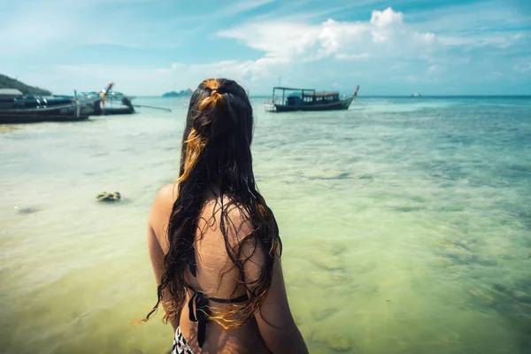 young female tourist in bikini taking a bath in the indian ocean of thailand from behind