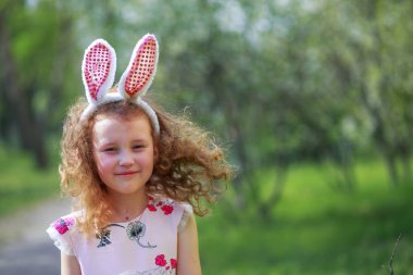 Paskalya gününde tavşan kulağı takan şirin bir çocuk. Baharda çiçek açan bahçelerin arka planında güzel kıvırcık saçlı kız.