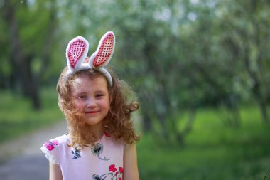 Paskalya gününde tavşan kulağı takan şirin bir çocuk. Baharda çiçek açan bahçelerin arka planında güzel kıvırcık saçlı kız.