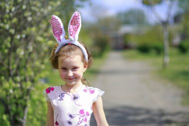 Paskalya gününde tavşan kulağı takan şirin bir çocuk. Baharda çiçek açan bahçelerin arka planında güzel kıvırcık saçlı kız.