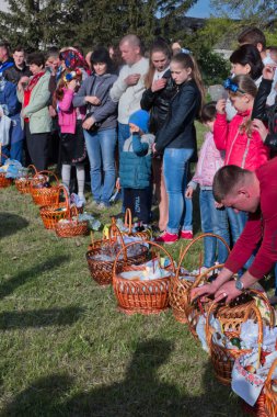 Kutsal su ile kutsanmış Paskalya pastaları. Paskalya için işlenmiş havlularla dolu birkaç sepet. Kadınlar sepetlerin yanında duruyorlar. Mumlar yanıyor..